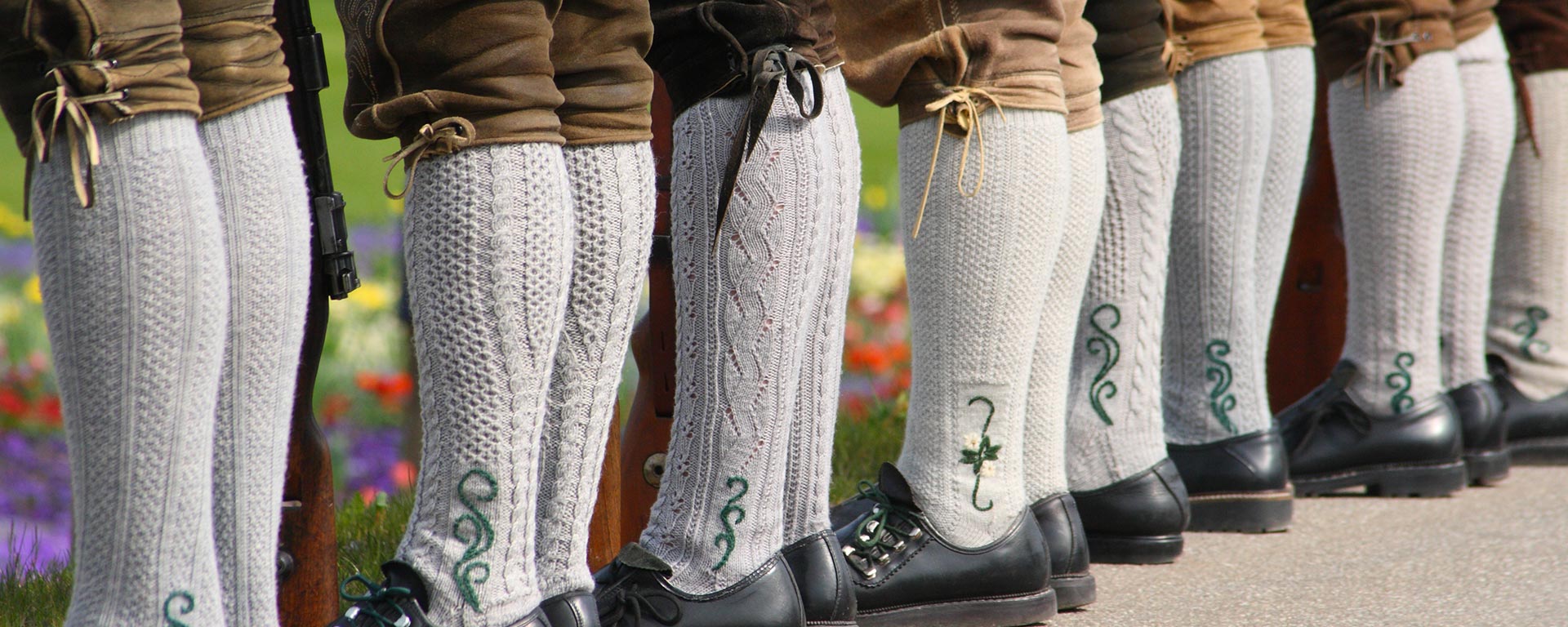 Dettaglio su alcuni uomini con Lederhosen, i tradizionali pantaloni di cuoio sudtirolesi, e calzettoni di lana bianchi con ricamo di colore verde durante una festa folcloristica a San Vigilio di Marebbe