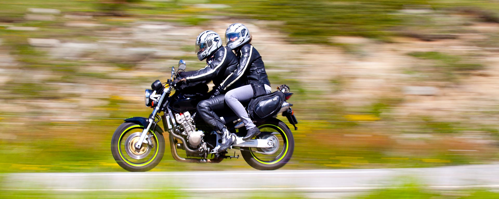 a couple riding a black motorbike at high speed