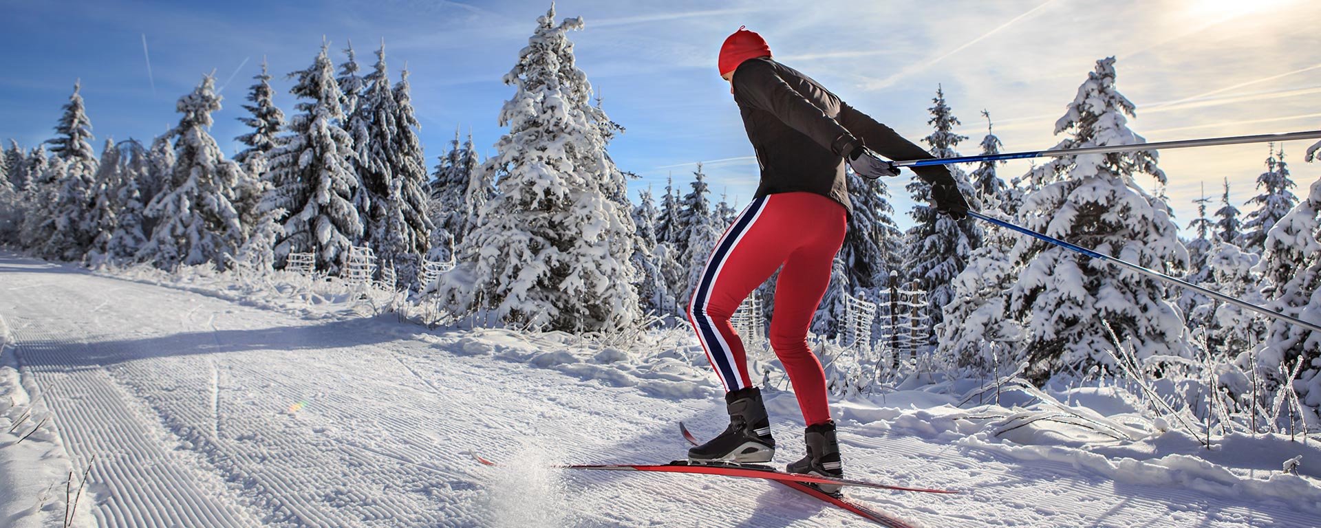 a man dressed in red and black is cross country skiing in the Dolomites