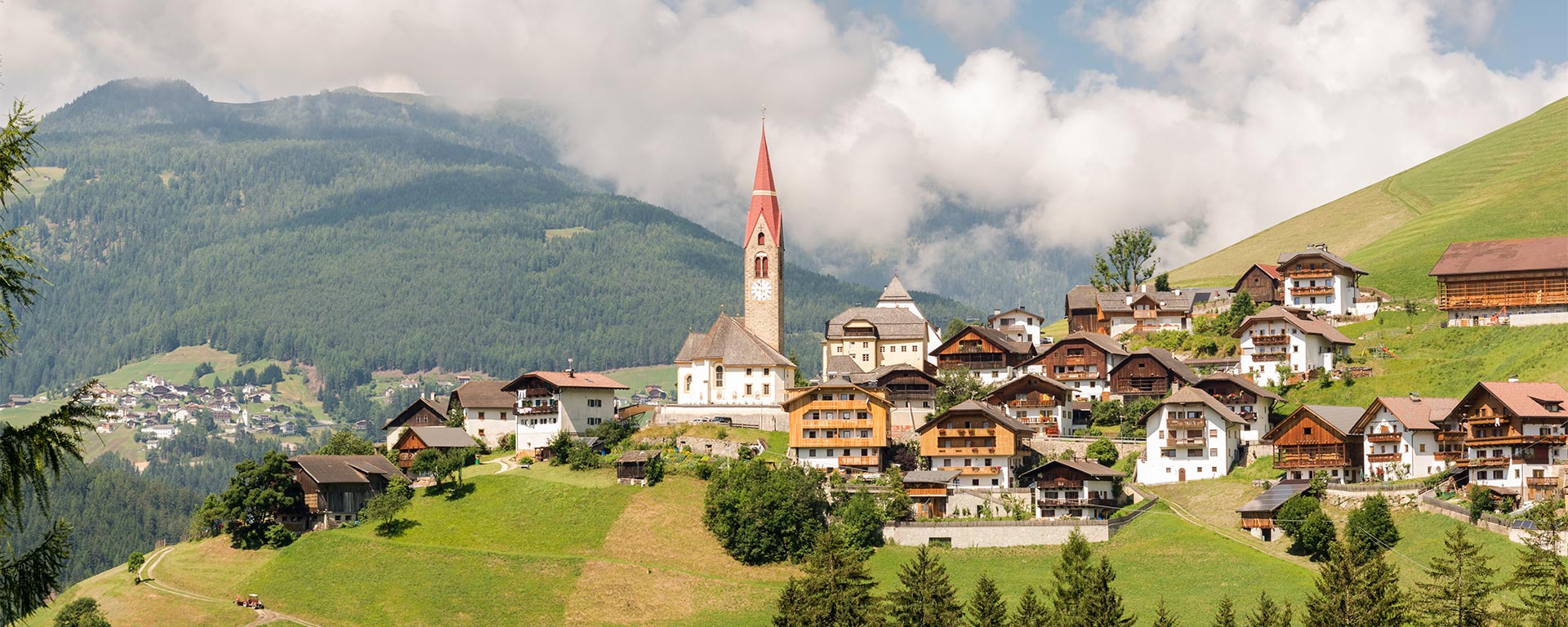 Una frazione del comune di Marebbe in estate con l'antica chiesa e le tipiche abitazioni in stile sudtirolese