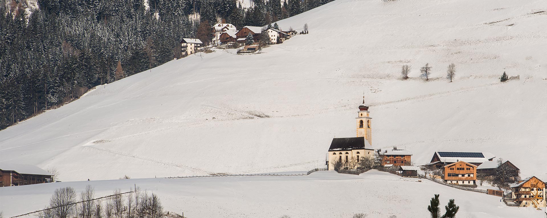 snow covered landscape around the church in San Vigilio di Marebbe in winter