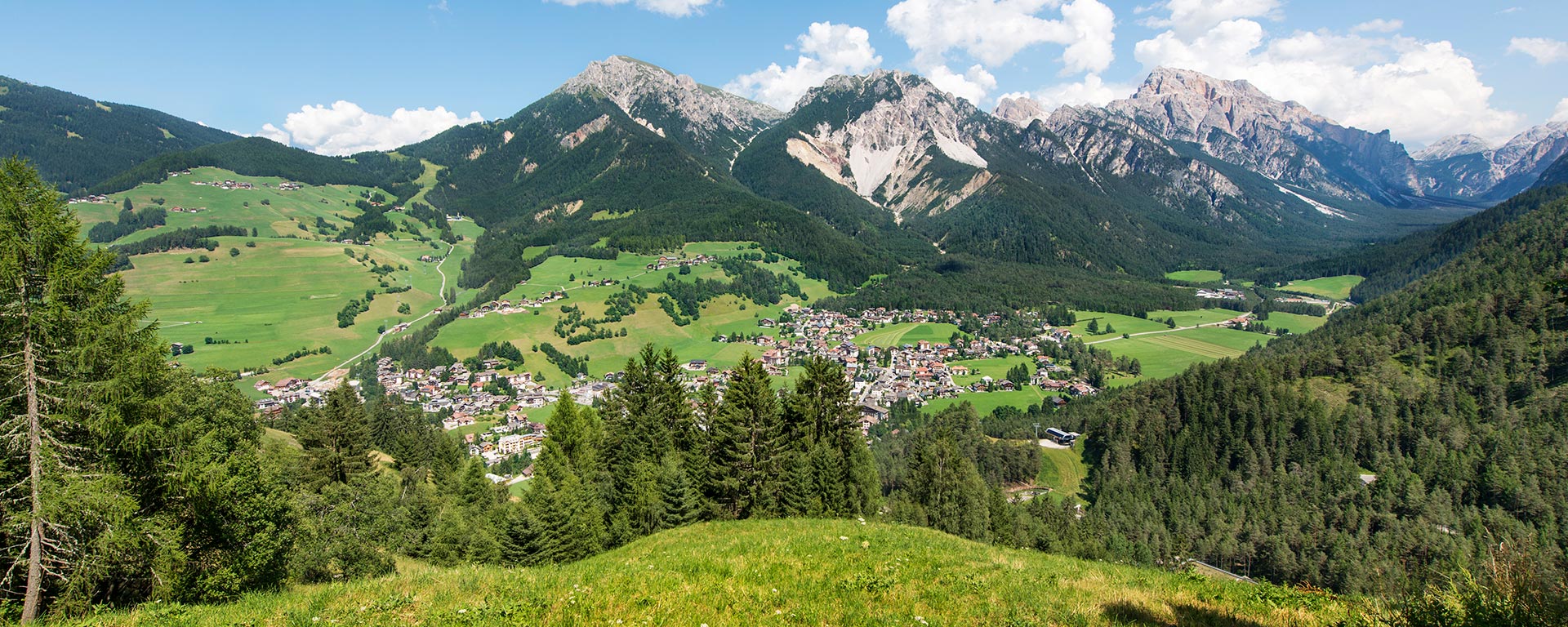 Blick auf die Ortschaft St. Vigil in Enneberg in Südtirol im Sommer mit günen Wiesen und Wäldern