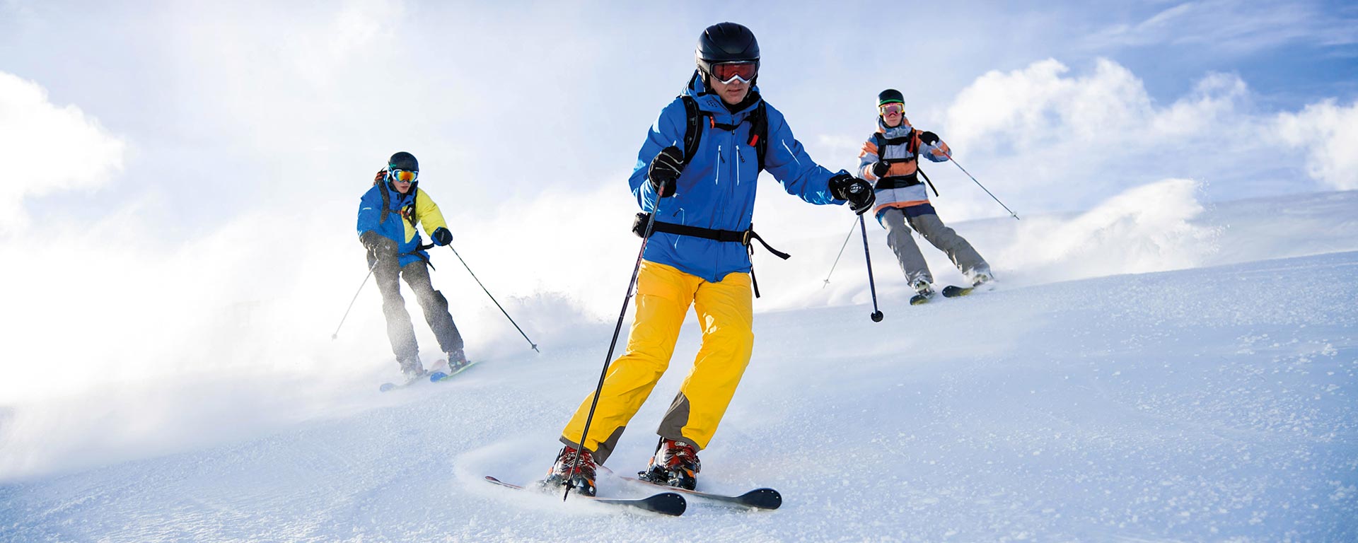 Tre ragazzi sciano sulla soleggiata pista Miara nel comprensorio sciistico Plan De Corones