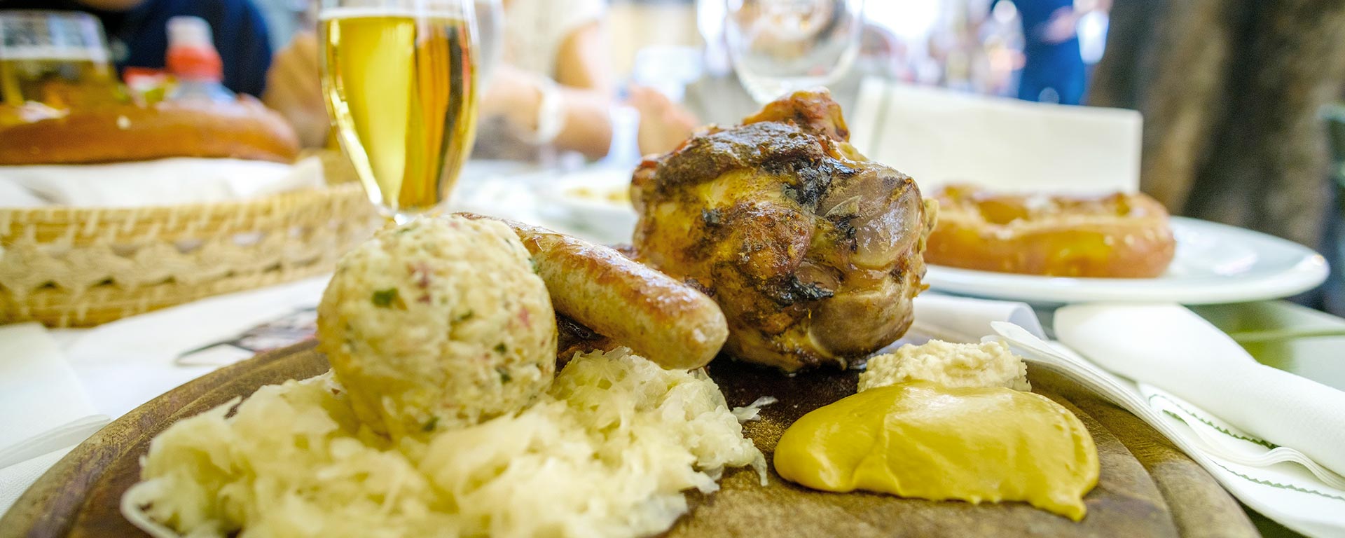 Typische Südtiroler Schlachtplatte aus Hauswurst, Schweinsstelze und Sauerkraut und ein Glas Bier