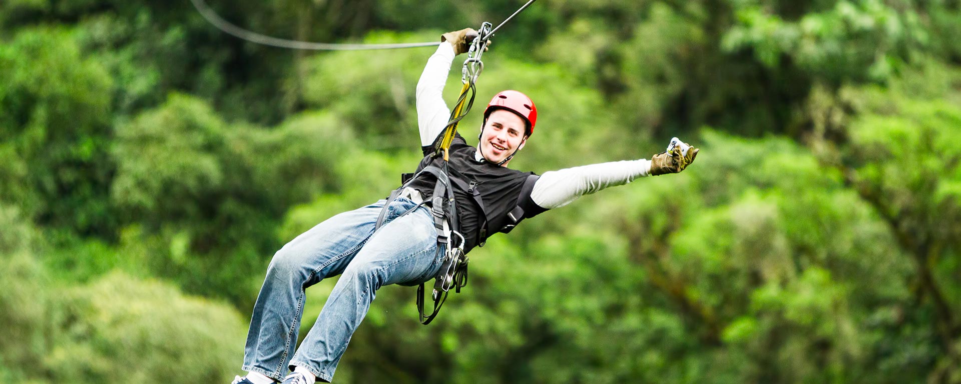 Junger Mann mit Karabinern und Seil an der Zipline in St. Vigil in Enneberg befestigt